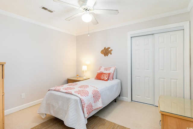 carpeted bedroom featuring ceiling fan, a closet, and crown molding