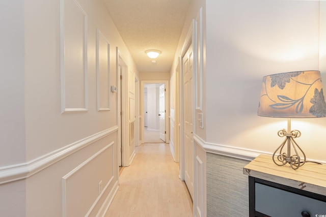 hall featuring light hardwood / wood-style flooring and a textured ceiling