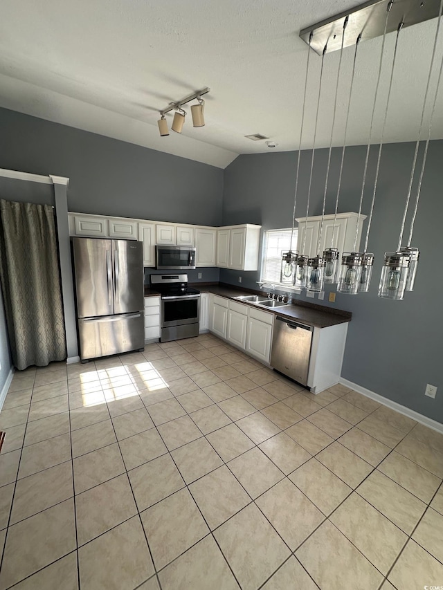 kitchen with light tile patterned floors, sink, appliances with stainless steel finishes, track lighting, and white cabinets