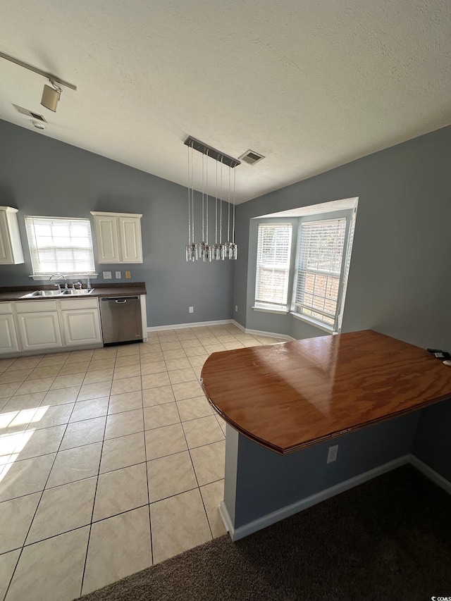 unfurnished dining area with sink, track lighting, a textured ceiling, light tile patterned flooring, and vaulted ceiling