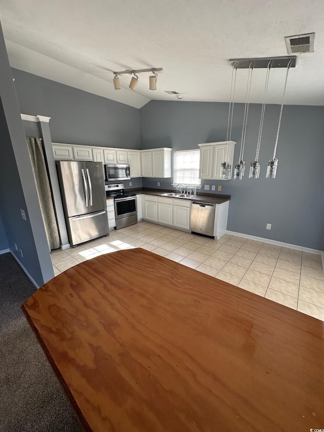 kitchen with sink, white cabinetry, hanging light fixtures, light tile patterned floors, and stainless steel appliances