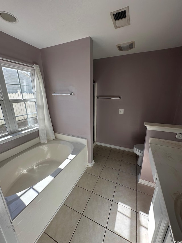 bathroom with vanity, tiled tub, tile patterned floors, and toilet