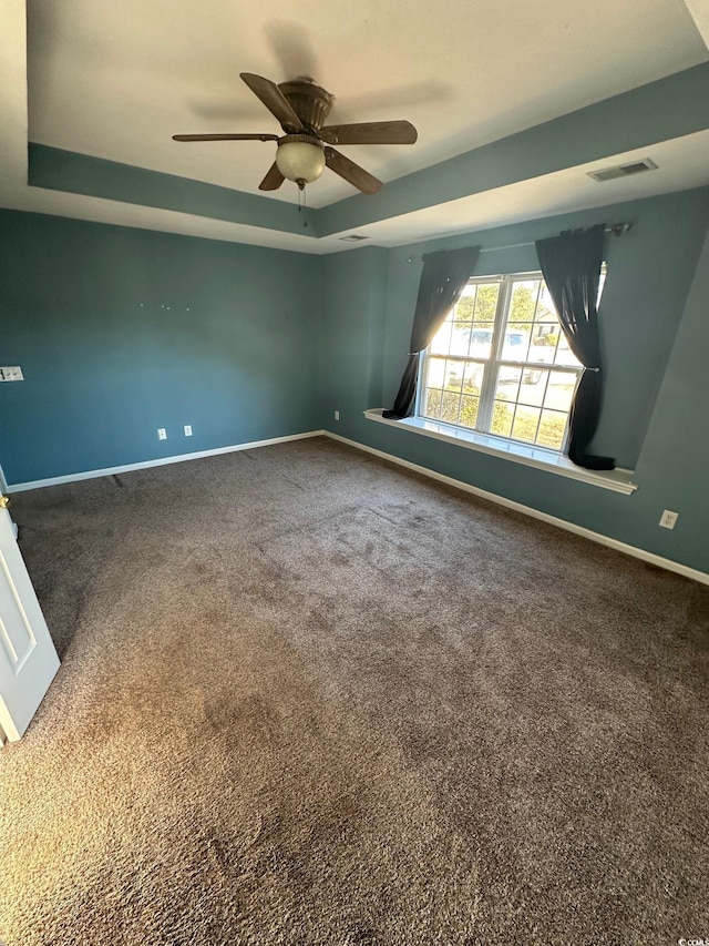 carpeted spare room with ceiling fan and a tray ceiling