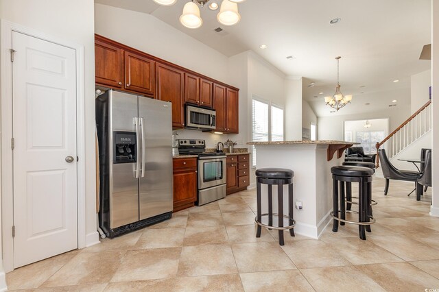 kitchen featuring a notable chandelier, a center island, appliances with stainless steel finishes, a kitchen breakfast bar, and pendant lighting