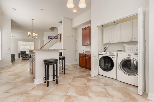 clothes washing area featuring independent washer and dryer, an inviting chandelier, and light tile patterned flooring