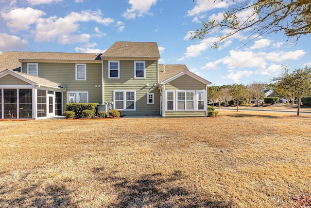 rear view of house featuring cooling unit, a lawn, and a sunroom