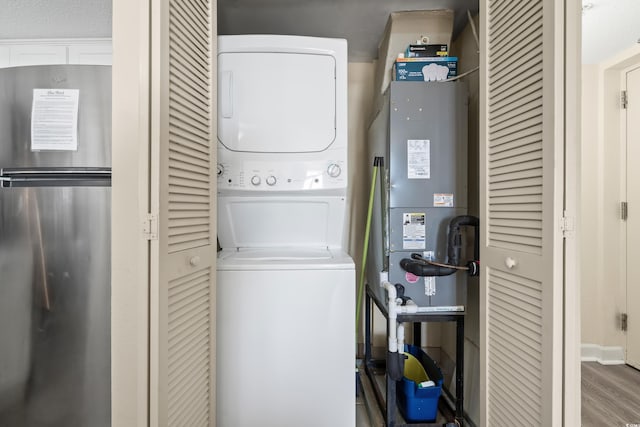 laundry room with stacked washer / dryer and wood-type flooring