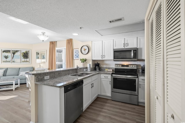 kitchen featuring sink, white cabinetry, dark hardwood / wood-style flooring, kitchen peninsula, and stainless steel appliances