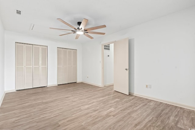 unfurnished bedroom with multiple closets, light wood-type flooring, and ceiling fan