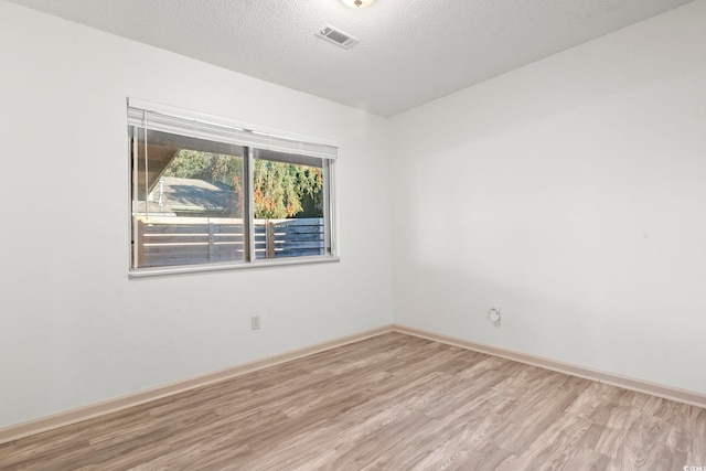 spare room with a textured ceiling and light hardwood / wood-style flooring