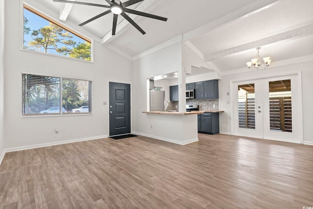 unfurnished living room with ceiling fan with notable chandelier, dark wood-type flooring, french doors, beamed ceiling, and high vaulted ceiling