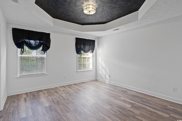 spare room featuring hardwood / wood-style flooring, a raised ceiling, and a textured ceiling