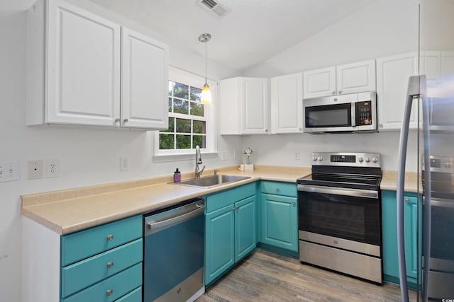 kitchen with white cabinetry, blue cabinetry, appliances with stainless steel finishes, and sink