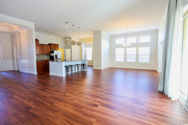 unfurnished living room with dark hardwood / wood-style flooring, crown molding, and a chandelier