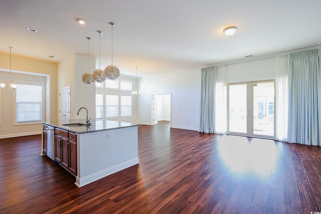 kitchen with decorative light fixtures, sink, dark hardwood / wood-style flooring, a center island with sink, and an inviting chandelier