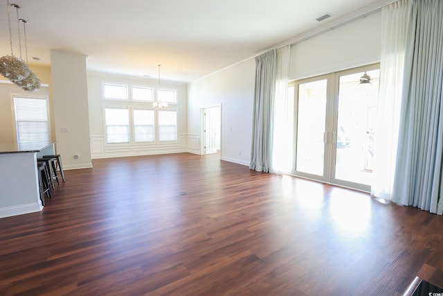 unfurnished living room with dark wood-type flooring, plenty of natural light, french doors, and a chandelier