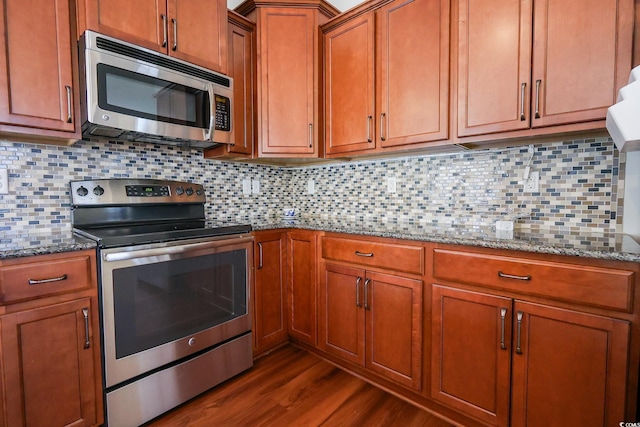 kitchen with tasteful backsplash, light stone countertops, appliances with stainless steel finishes, and dark wood-type flooring