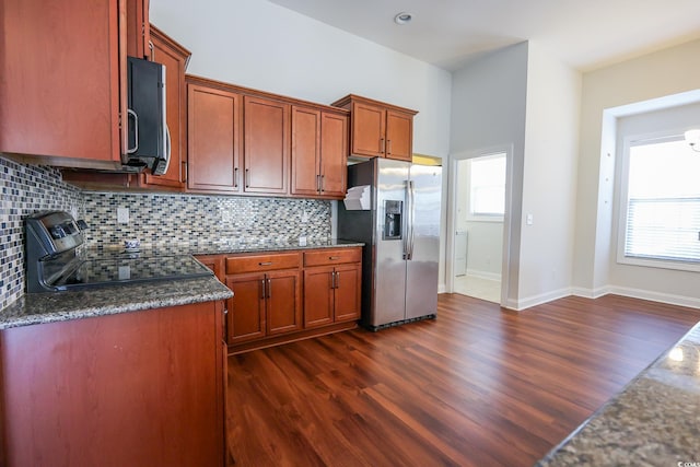 kitchen featuring stainless steel appliances, tasteful backsplash, dark hardwood / wood-style flooring, and dark stone counters