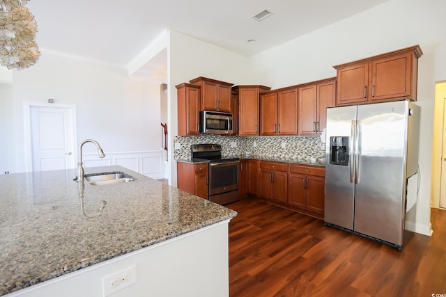 kitchen with sink, dark wood-type flooring, backsplash, stainless steel appliances, and light stone counters