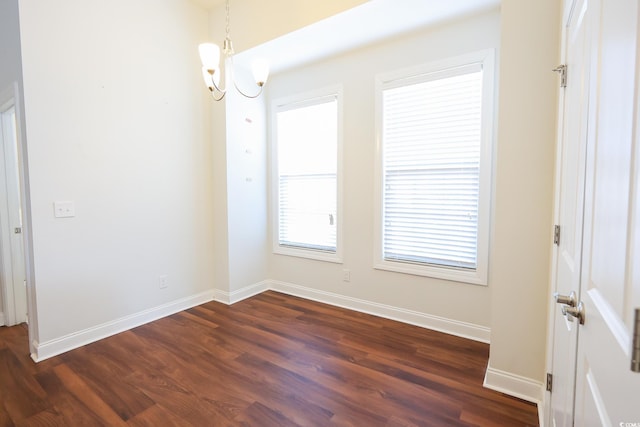 unfurnished room featuring dark hardwood / wood-style floors and a chandelier