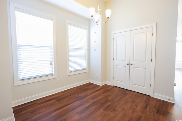 unfurnished room featuring dark wood-type flooring and a notable chandelier