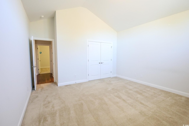 unfurnished bedroom with a closet, high vaulted ceiling, and light carpet