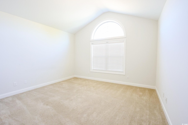 unfurnished room featuring light colored carpet and vaulted ceiling