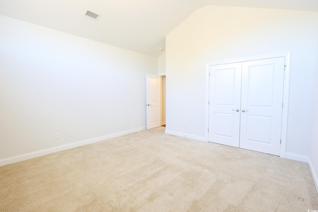 unfurnished bedroom with lofted ceiling, light colored carpet, and a closet