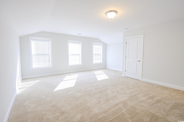 bonus room with lofted ceiling and light carpet