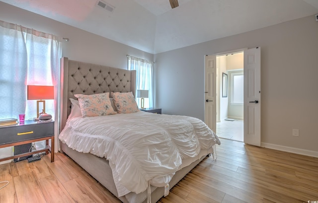 bedroom with ceiling fan, light hardwood / wood-style floors, and a tray ceiling