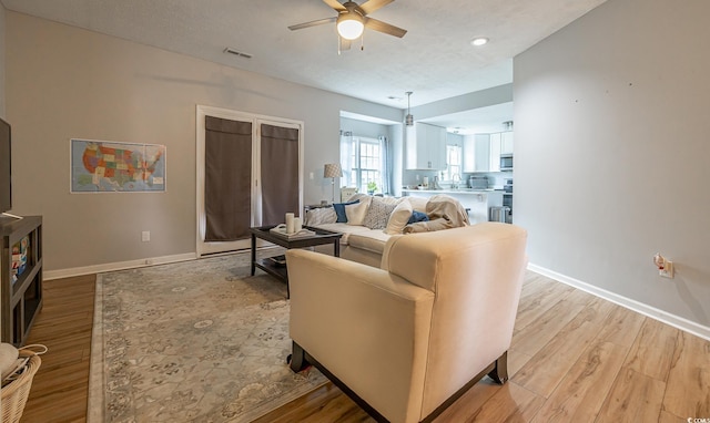 living room with ceiling fan, a textured ceiling, and hardwood / wood-style floors