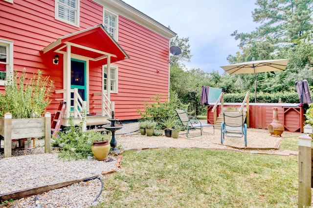 property entrance featuring a hot tub and a yard