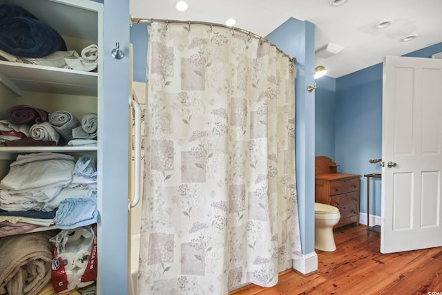 bathroom with hardwood / wood-style floors, toilet, and a shower with shower curtain