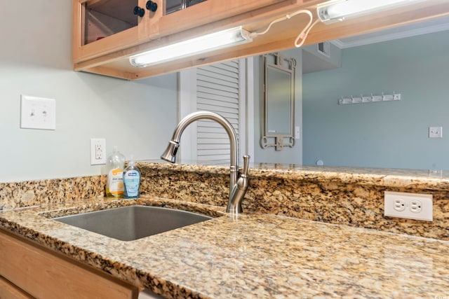 details with light stone counters, indoor bar, a sink, glass insert cabinets, and crown molding