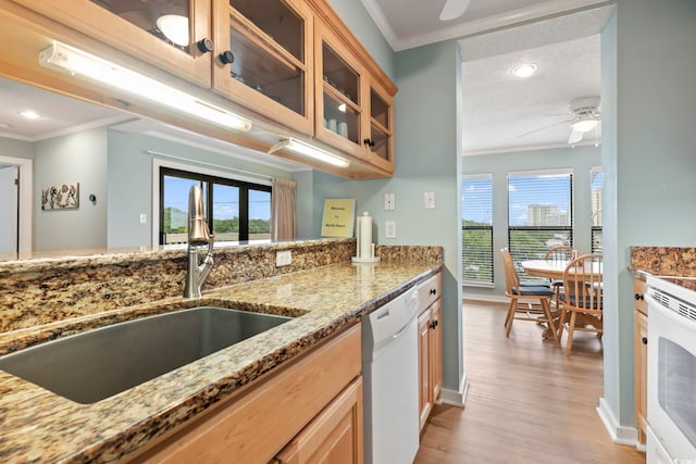 kitchen with ceiling fan, light stone countertops, white dishwasher, crown molding, and a sink