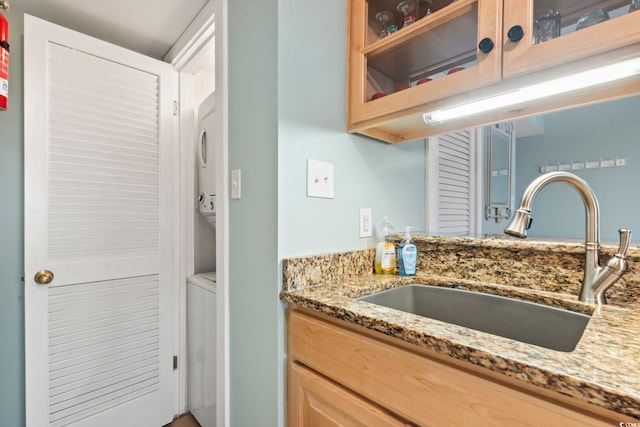 kitchen featuring a sink, glass insert cabinets, and light stone countertops