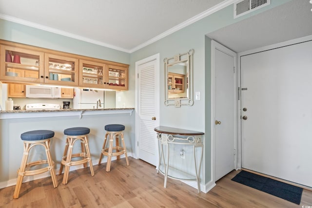 kitchen featuring light wood-type flooring, white microwave, visible vents, and crown molding