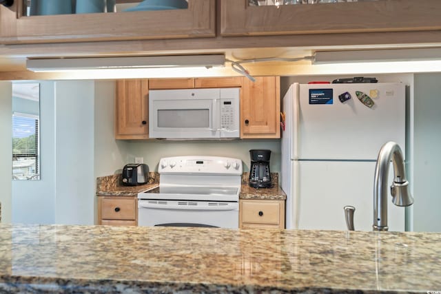 kitchen featuring white appliances and light stone countertops