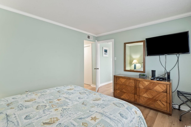 bedroom featuring ornamental molding, light wood-type flooring, and visible vents