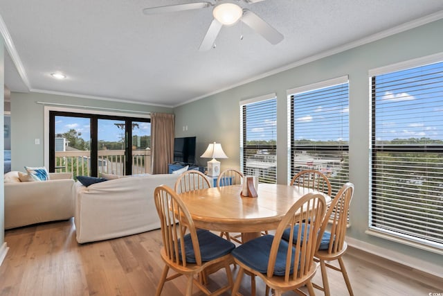 dining area with a textured ceiling, light wood-style floors, a healthy amount of sunlight, and crown molding