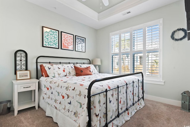 bedroom featuring ceiling fan, carpet flooring, a tray ceiling, and multiple windows