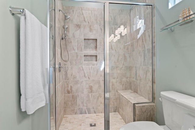 bathroom featuring toilet and a shower with shower door