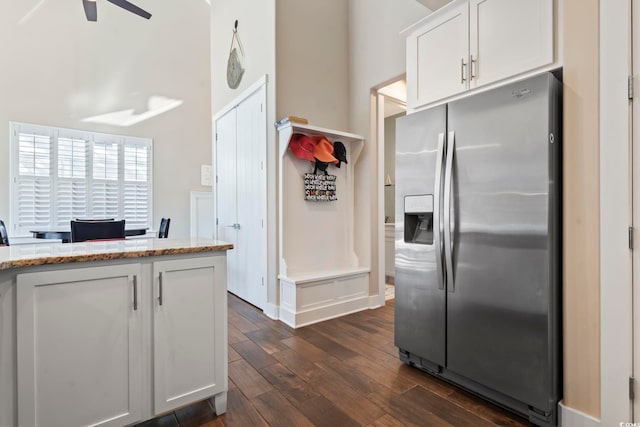 kitchen with stainless steel refrigerator with ice dispenser, light stone counters, white cabinets, and dark hardwood / wood-style flooring