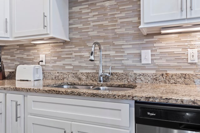 kitchen featuring dishwasher, decorative backsplash, sink, white cabinetry, and light stone countertops