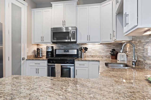 kitchen with backsplash, sink, stainless steel appliances, and white cabinetry