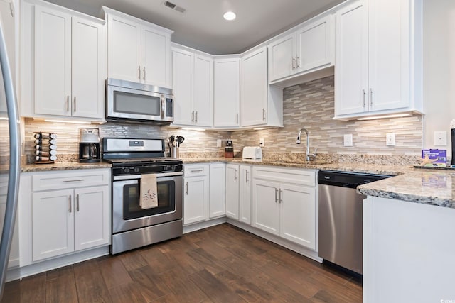 kitchen featuring white cabinetry, appliances with stainless steel finishes, backsplash, light stone counters, and sink