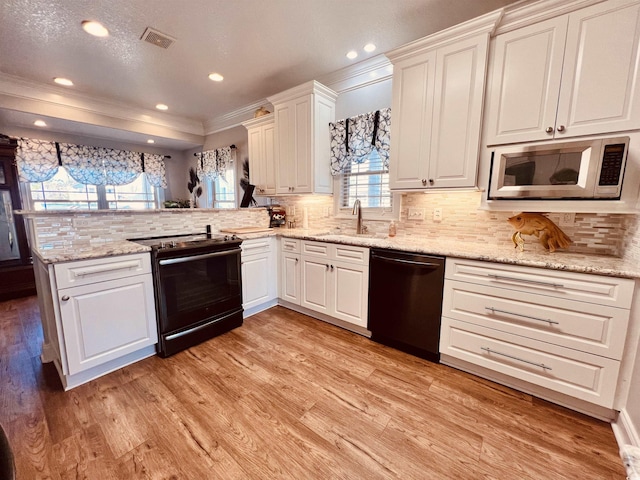 kitchen with kitchen peninsula, sink, backsplash, light wood-type flooring, and black appliances