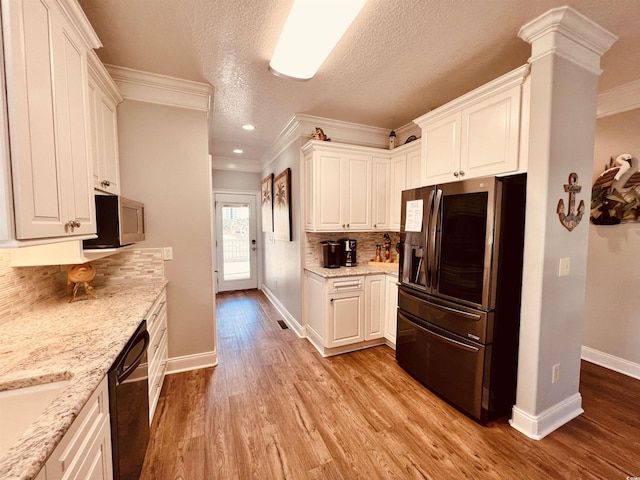 kitchen with white cabinets, backsplash, ornamental molding, and appliances with stainless steel finishes