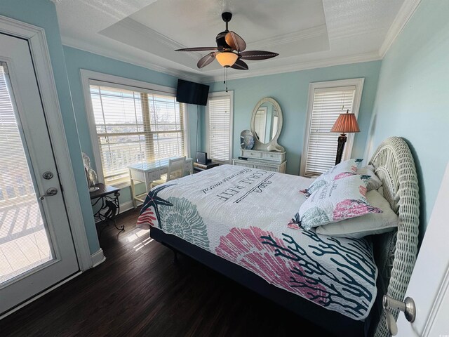 bedroom featuring ceiling fan, ornamental molding, a tray ceiling, and dark hardwood / wood-style flooring