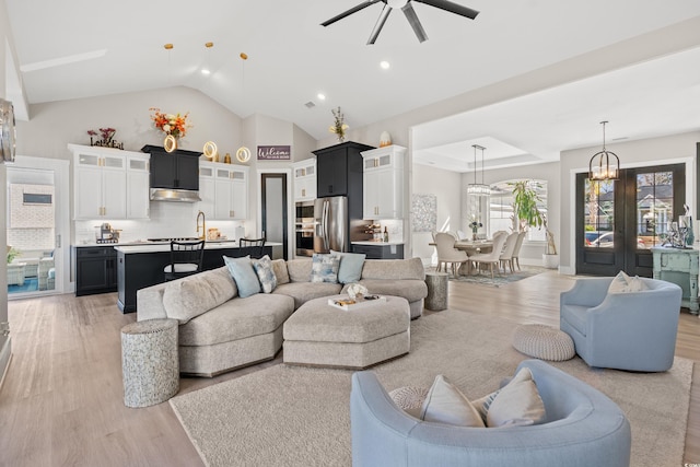 living room with high vaulted ceiling, ceiling fan, and light hardwood / wood-style flooring